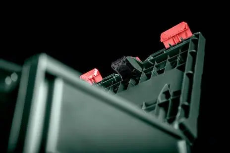 An image of a Metabo Metaloc case with the Metabo GPS Tracker shown attached to lid. The background of the image is black.