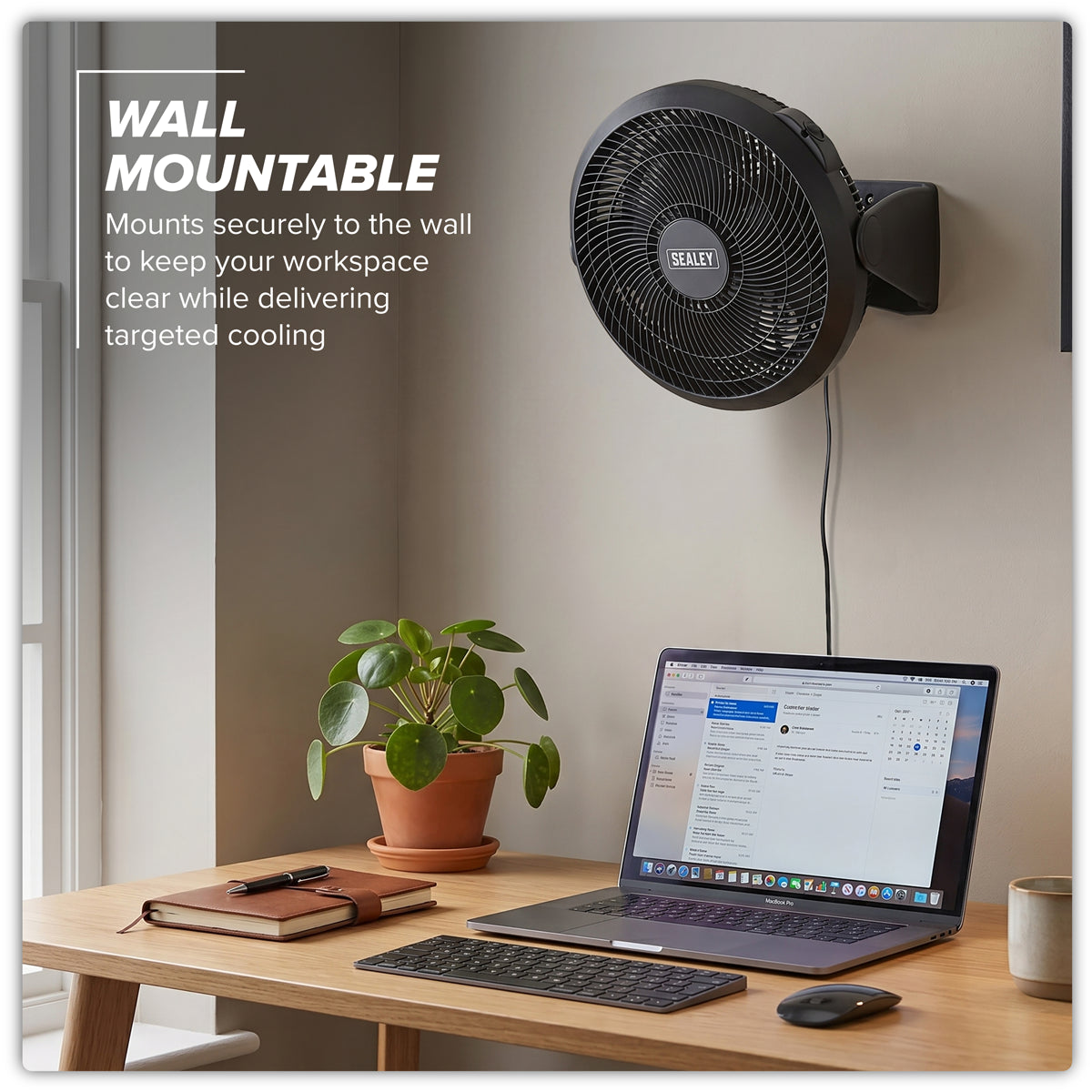 Wall-mounted Sealey fan above a desk with laptop and plant