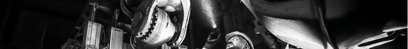 Image of a man shining a torch upwards towards some machinery.