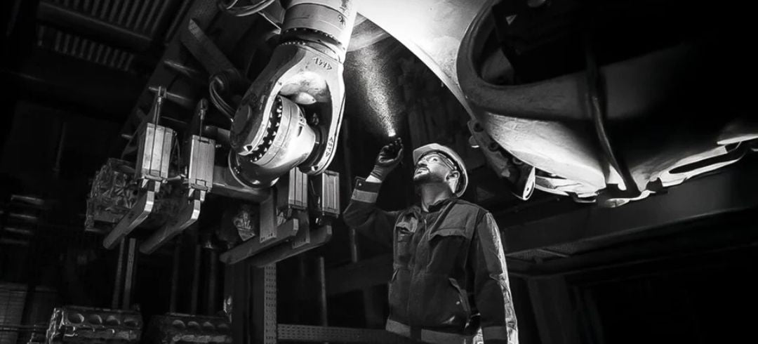 Image of a man shining a torch upwards towards some machinery.