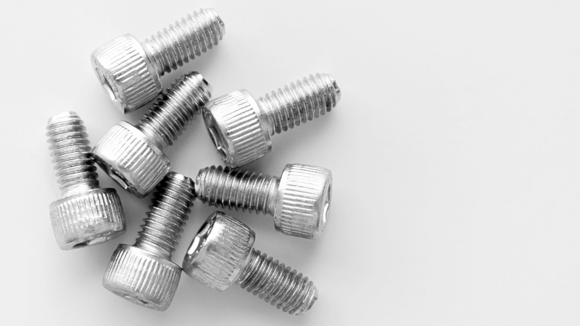 A simple icon of a socket screw in white on a red background