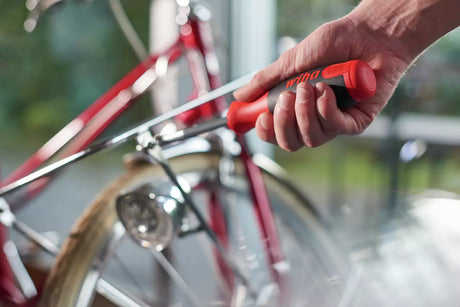Person using a red Wiha LiftUp 25 screwdriver on a bicycle