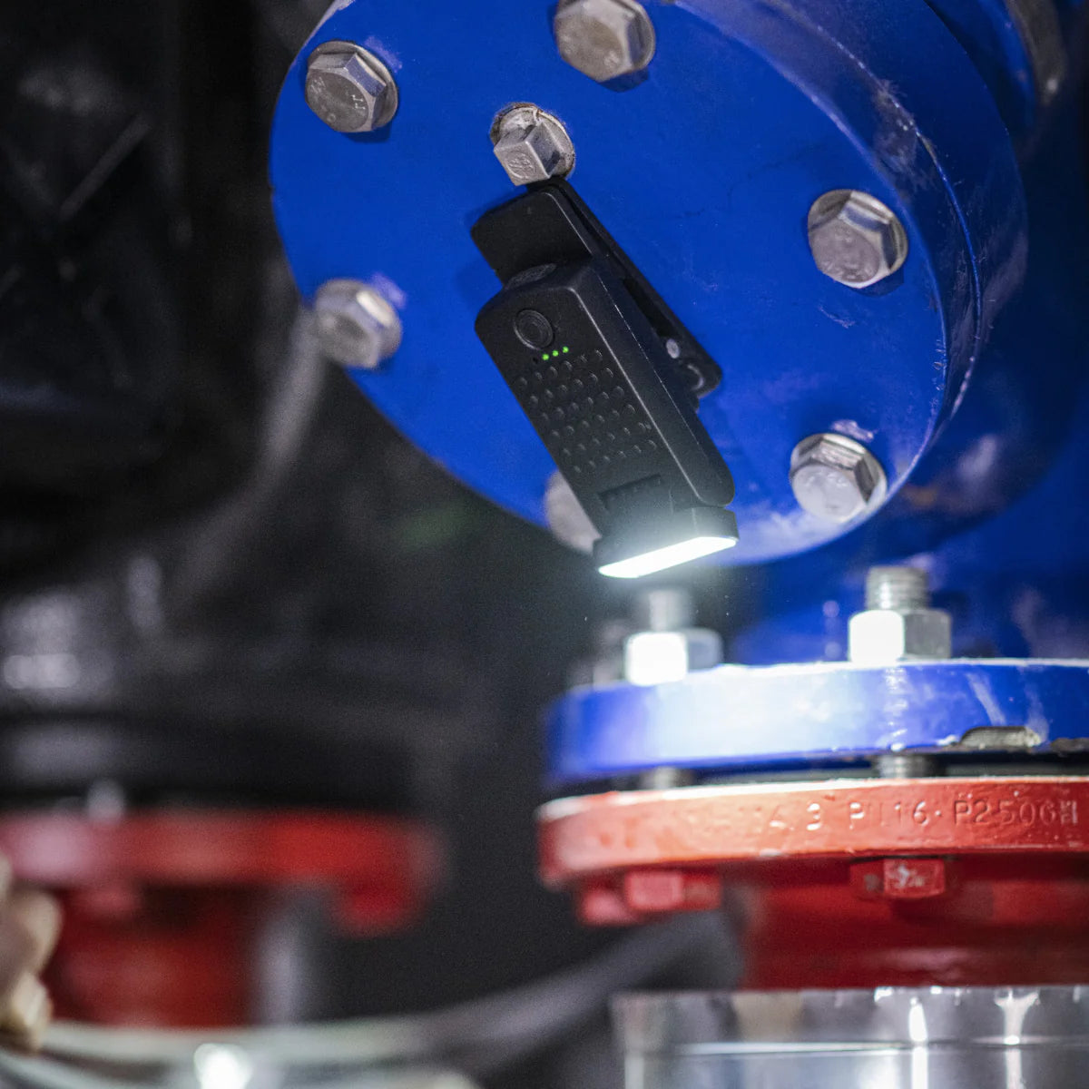 Close-up of a blue mechanical component with a black device attached, possibly for measurement or inspection.