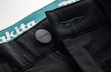 Close-up of the Black Makita Onyx 4 way stretch trousers showing a Makita button with logo on a white background