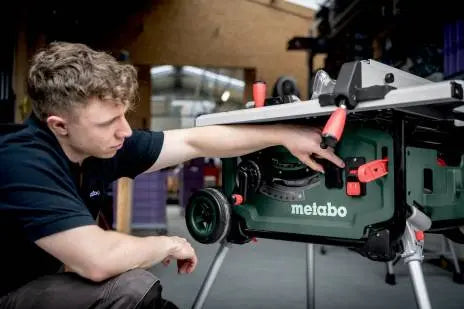 Image showing a person attaching the Metabo GPS Tracker to a metabo table saw. He is in a workshop. 