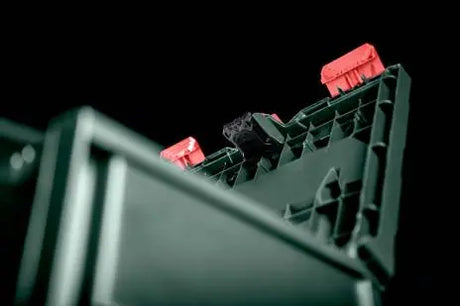 An image of a Metabo Metaloc case with the Metabo GPS Tracker shown attached to lid. The background of the image is black. 