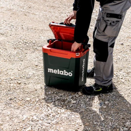 Person opening a Metabo coolbox on a gravel surface