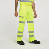 Person wearing high-visibility yellow work pants with reflective stripes on a white background