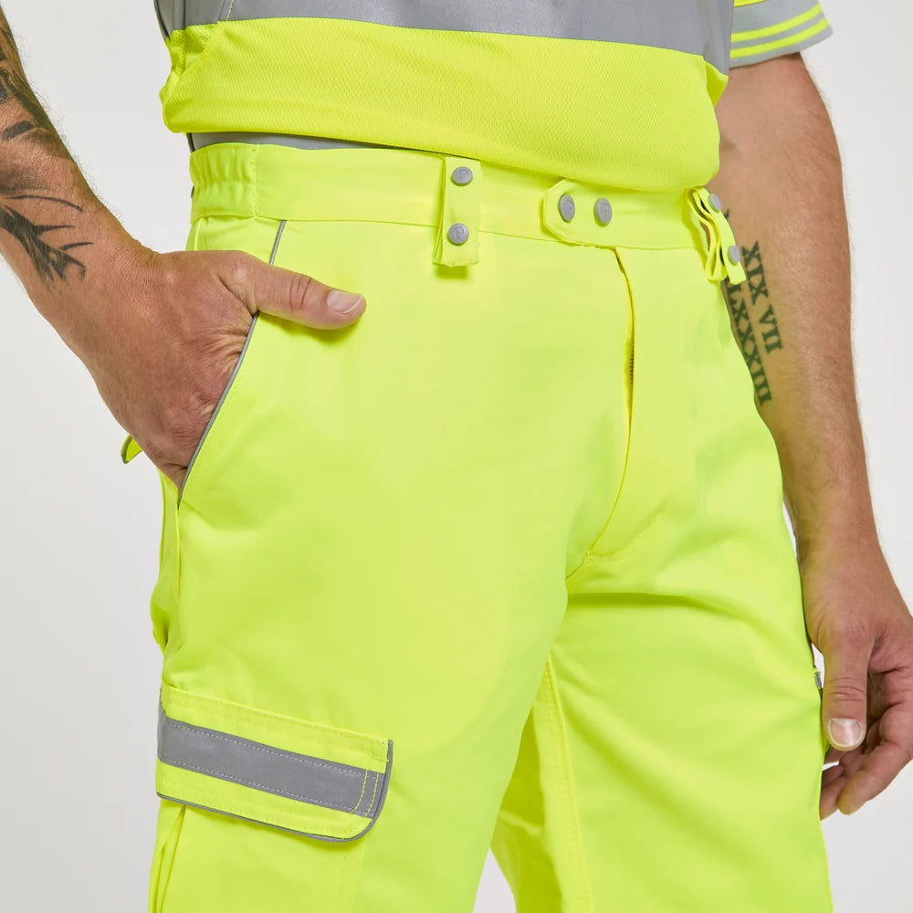 Person wearing bright yellow safety pants with reflective stripes on a plain background