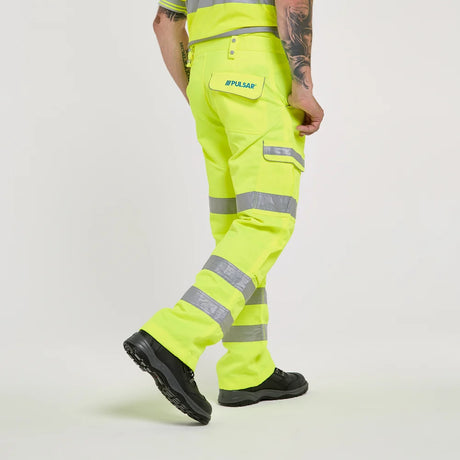 A model from the waist down wearing high-visibility neon yellow safety trousers with reflective silver stripes and cargo pockets, standing against a light gray studio background.