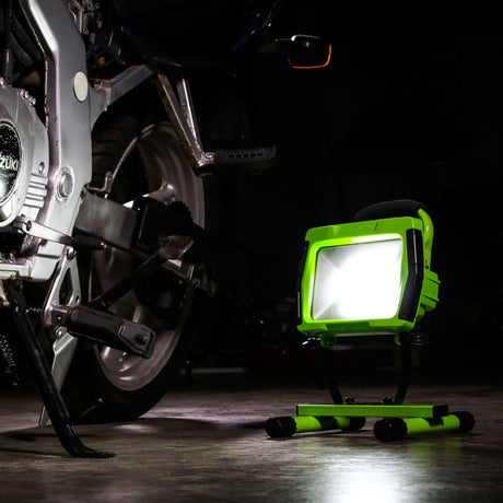 Green work light next to a motorcycle in a dark setting