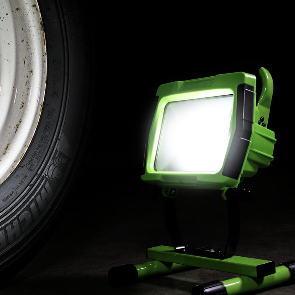Green work light next to a tire on a dark background