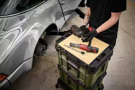 Person working on a car with tools on a portable workbench