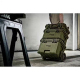 Person pushing a stack of green Bunker cases in an industrial setting