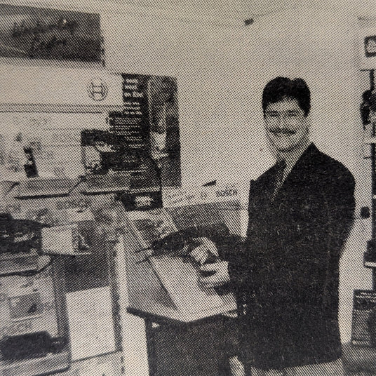 Person with a questionable moustache standing in a room with tools and equipment on the floor